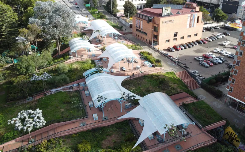 Aerial view of the serpentine canopy system with planted terraces between curved pavilion roofs and adjacent parking