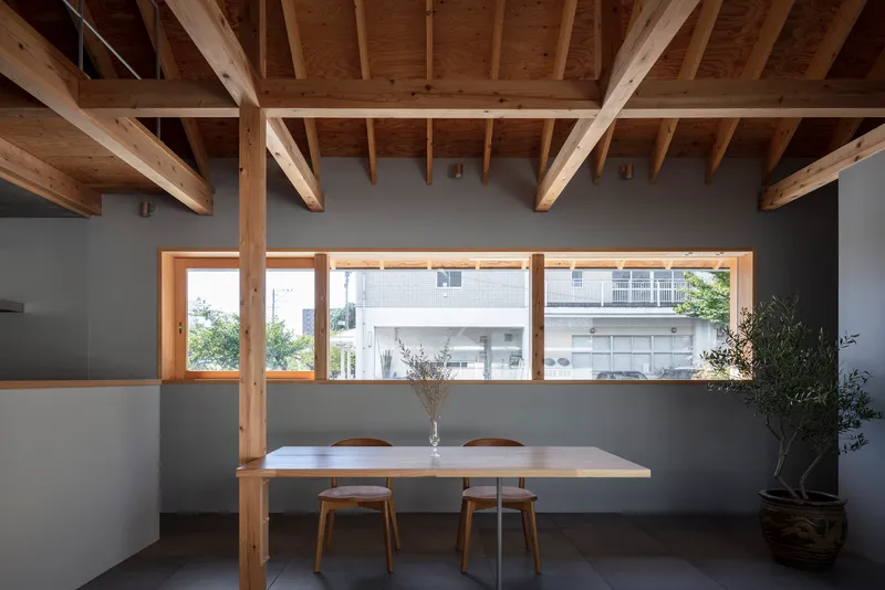 Interior dining space with horizontal window framing a view of the neighboring buildings beyond