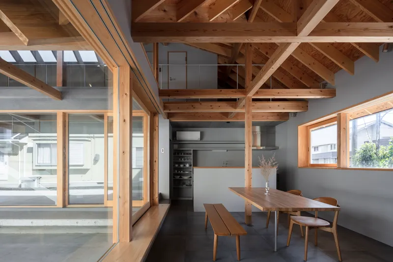 Kitchen and dining space beneath exposed timber rafters with glazed sliding doors to adjacent rooms