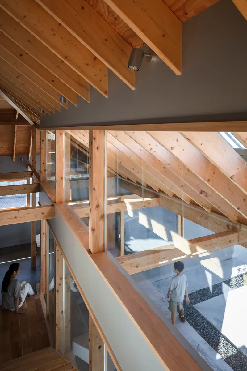View through timber framing to courtyard below where a person stands in sunlight