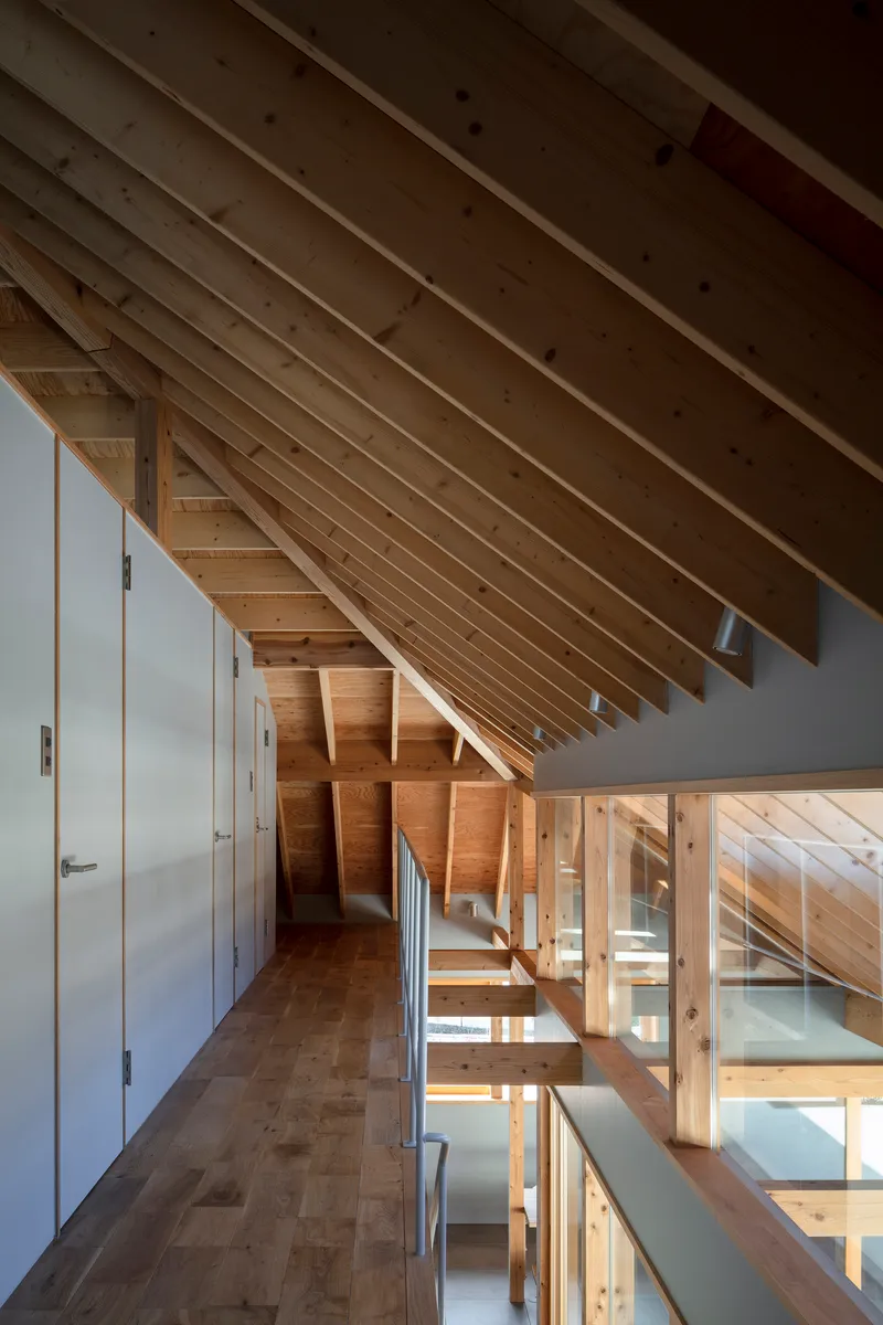 Upper level hallway with exposed timber roof beams and glass-paneled railing overlooking the floors below