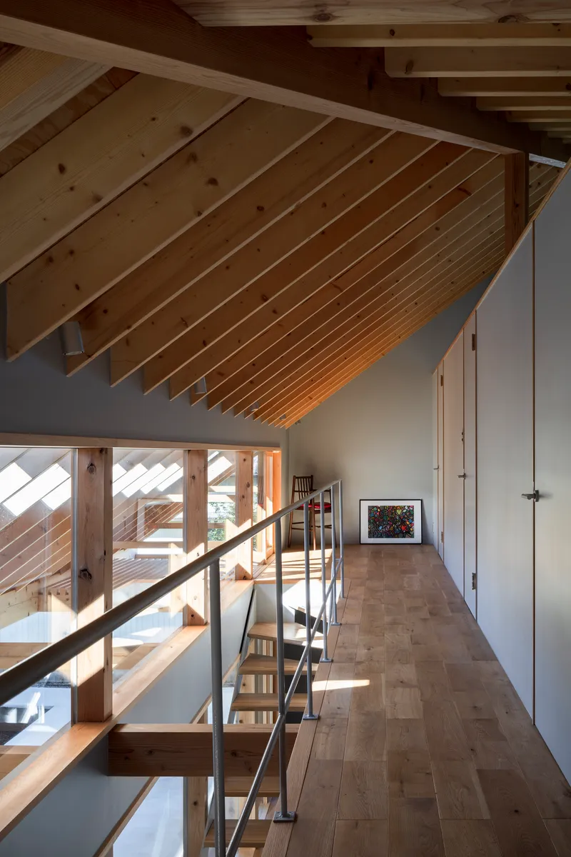 Mezzanine corridor with sloped timber ceiling and steel handrail along the open edge in morning light