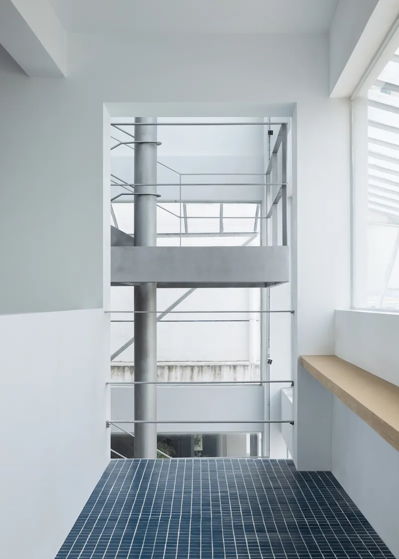 Interior balcony with blue mosaic tile floor overlooking a multi-level atrium with steel railings