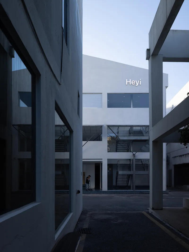 Courtyard view between white volumes with external steel staircases and bridges connecting upper floors