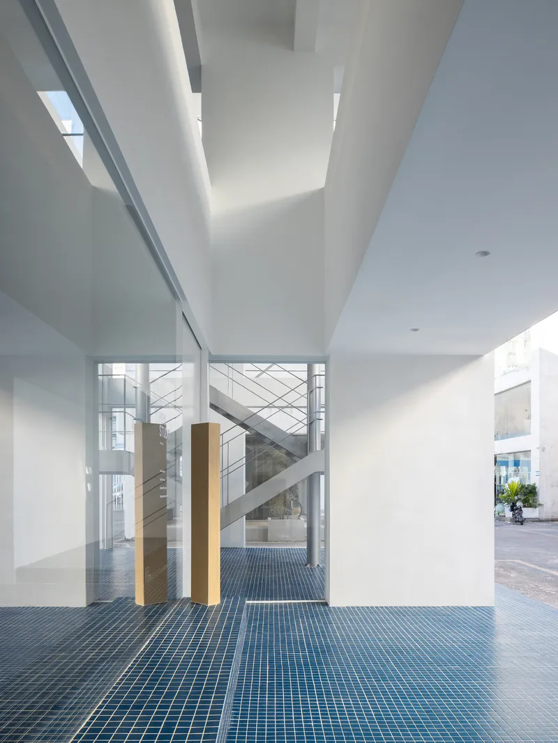 View through glass walls toward internal staircase framed by timber columns and white ceiling beams