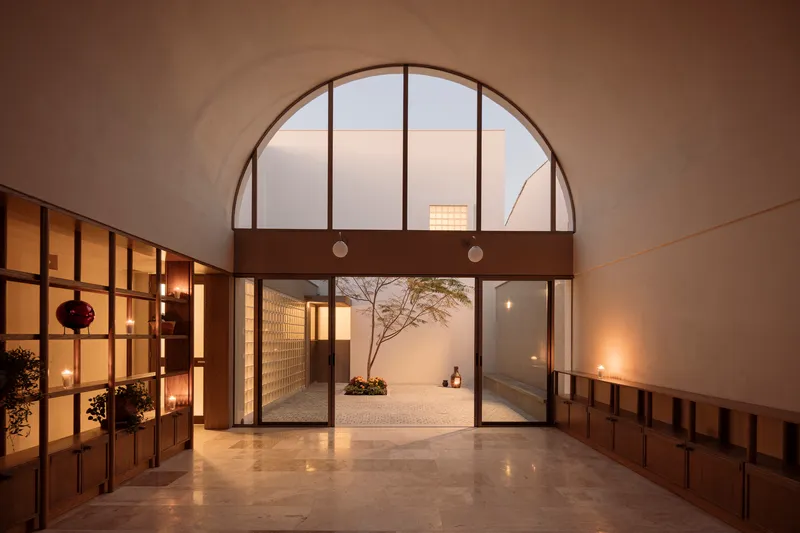 Entry hall looking through an arched opening to a glass block courtyard wall at dusk