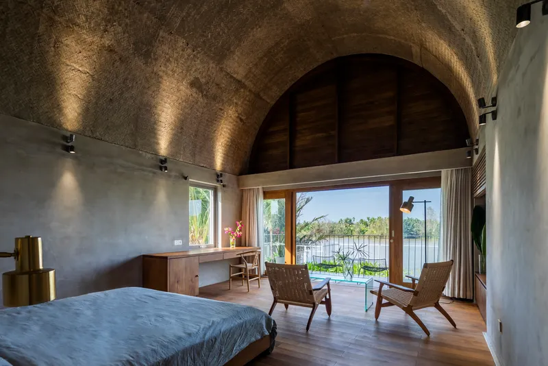Vaulted bedroom with glazed doors opening to a terrace overlooking the water
