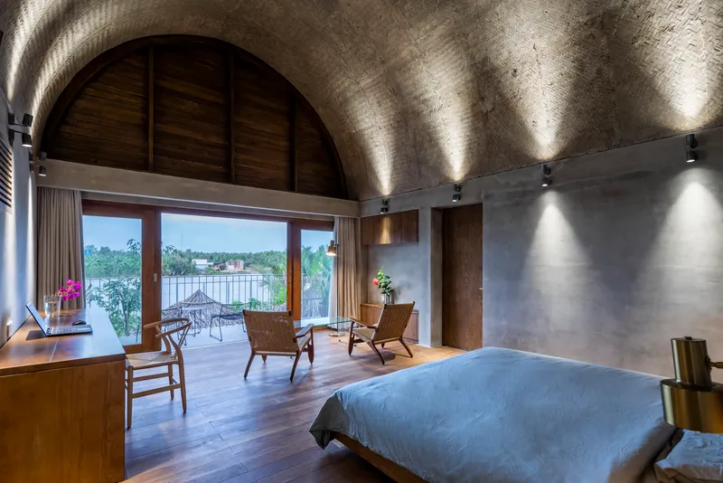 Bedroom with barrel vaulted concrete ceiling and timber-framed doors opening to a lakeside terrace