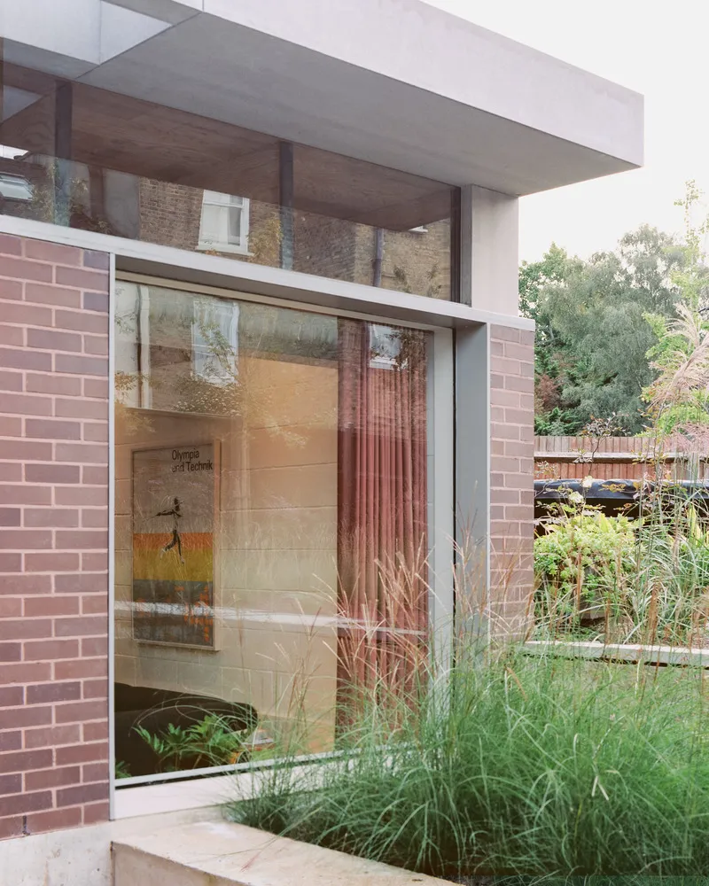 Glazed corner framed by pink brick walls looking onto the planted rear garden