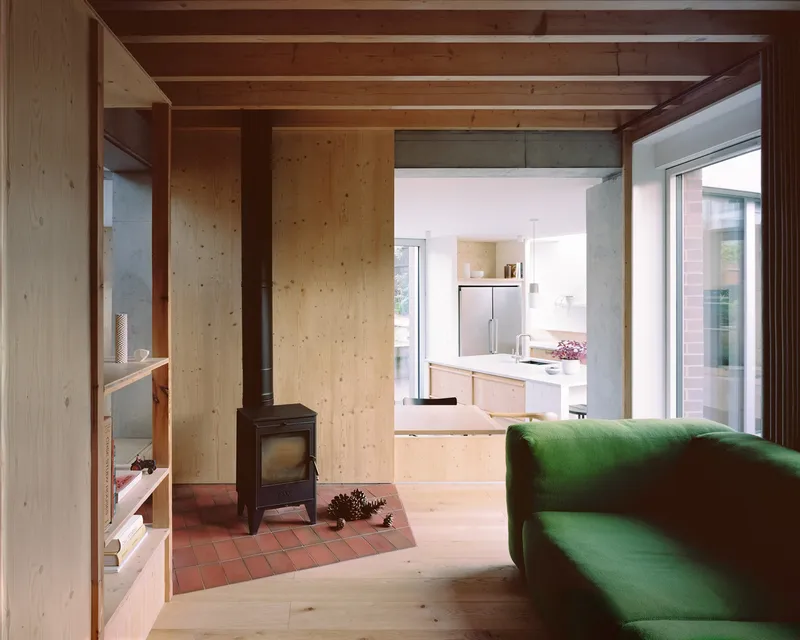 Living space with wood stove on terracotta tile hearth and view through to the kitchen