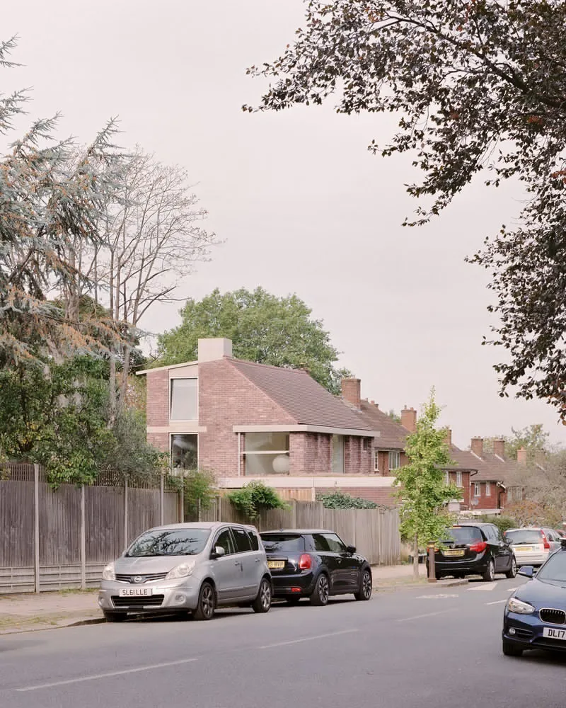 Distant street view of the pitched roof house among trees and parked cars