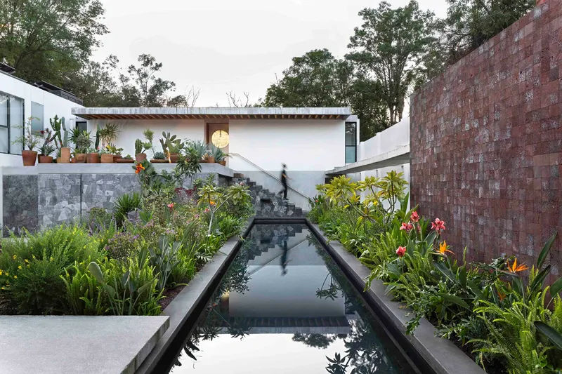 Long lap pool running between planted beds toward the upper terrace and main house