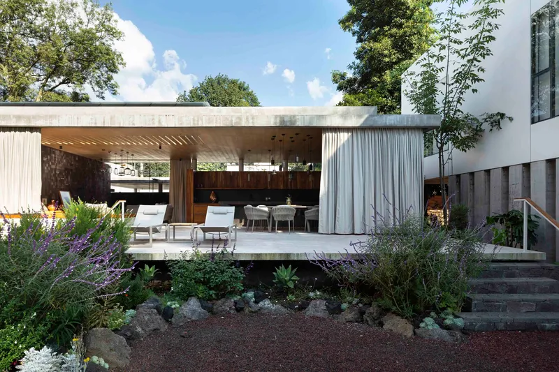 View of the open pavilion across the wild planted garden with curtains drawn back