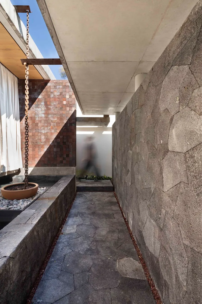Narrow side passage with stone-clad wall and a stone-floor path leading to the rear