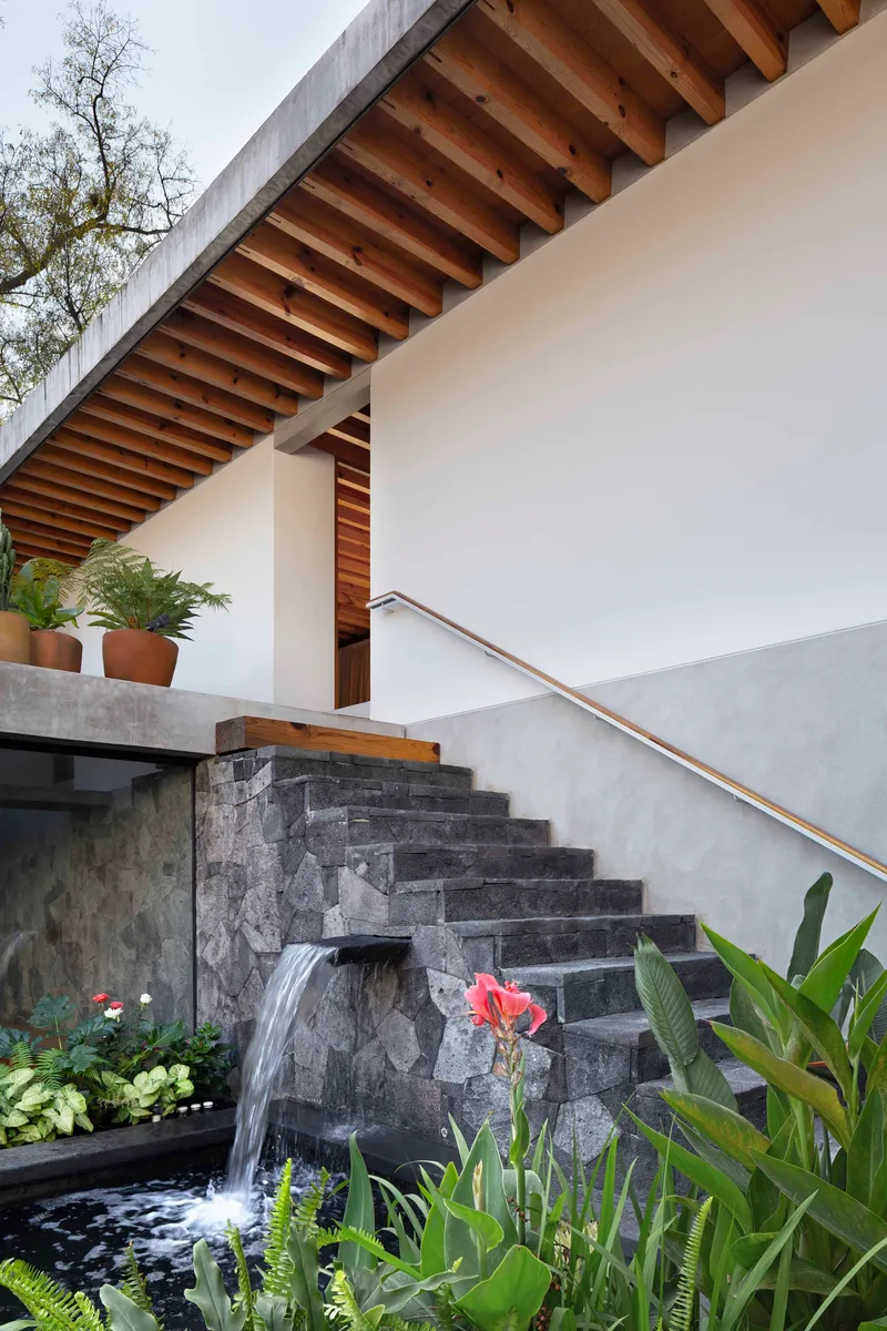 Stone stair with a small water cascade beside it and an exposed timber soffit above