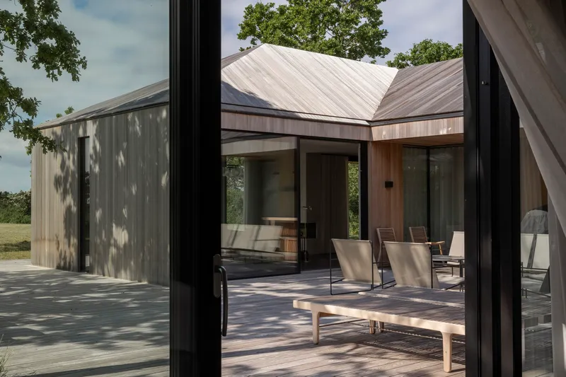 Timber courtyard with standing seam metal roofs visible through glazed corner opening