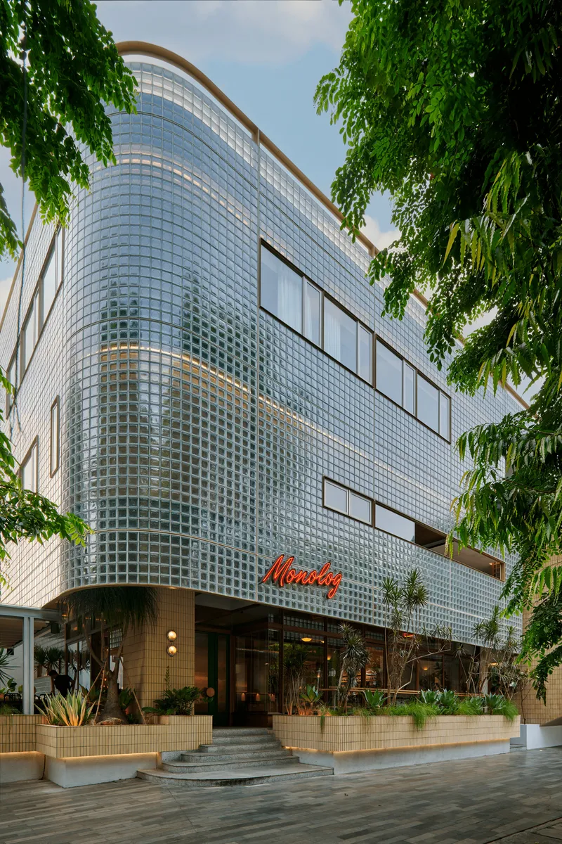 Curved glass block facade rising three stories above the ground level entrance and planted terrace