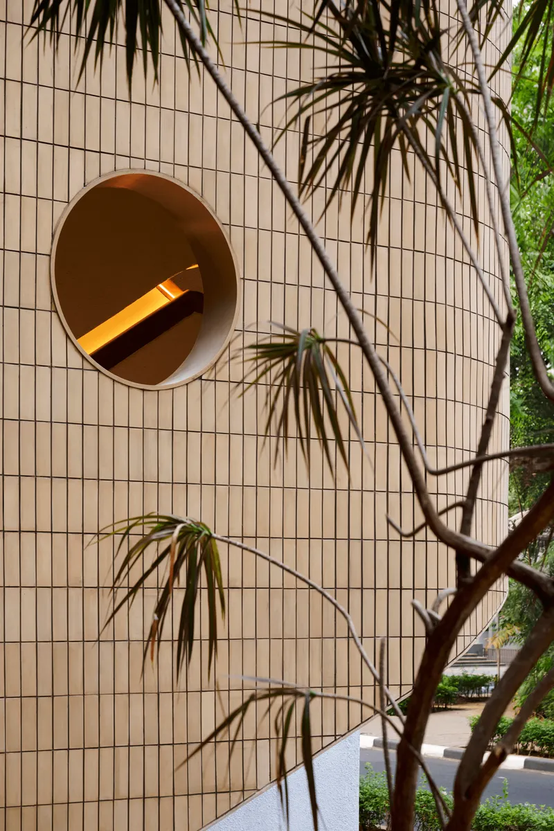 Circular portal set into vertical tile wall with palm fronds casting shadows from adjacent tree