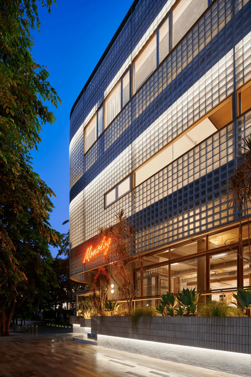 Street view of glass block facade with recessed window openings at twilight