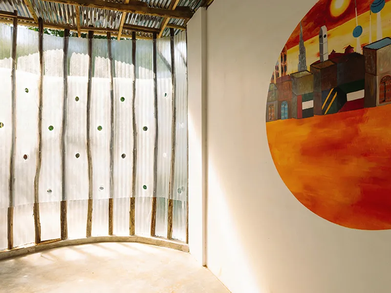Detail of curved translucent wall with circular glass openings and a painted mural on adjacent surface