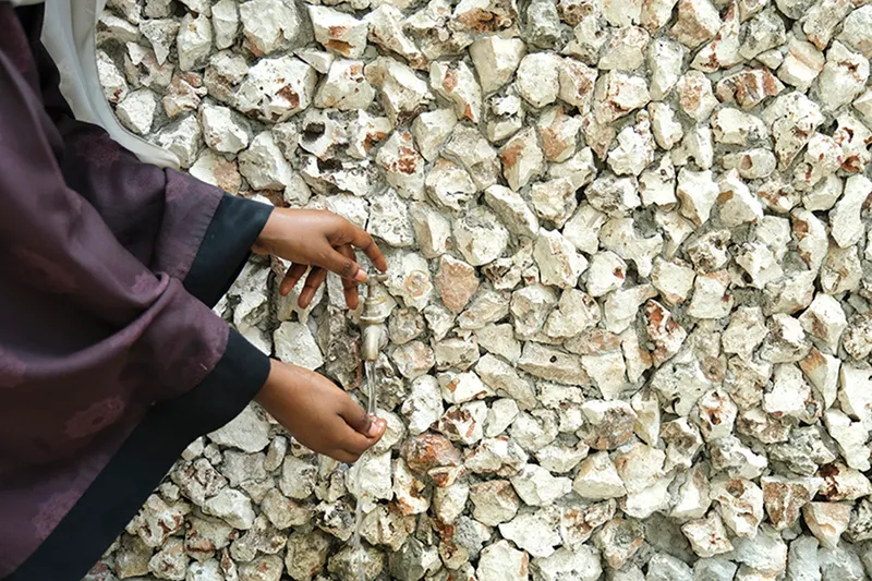 Hands touching a wall surface composed of white crushed coral or oyster shell aggregate