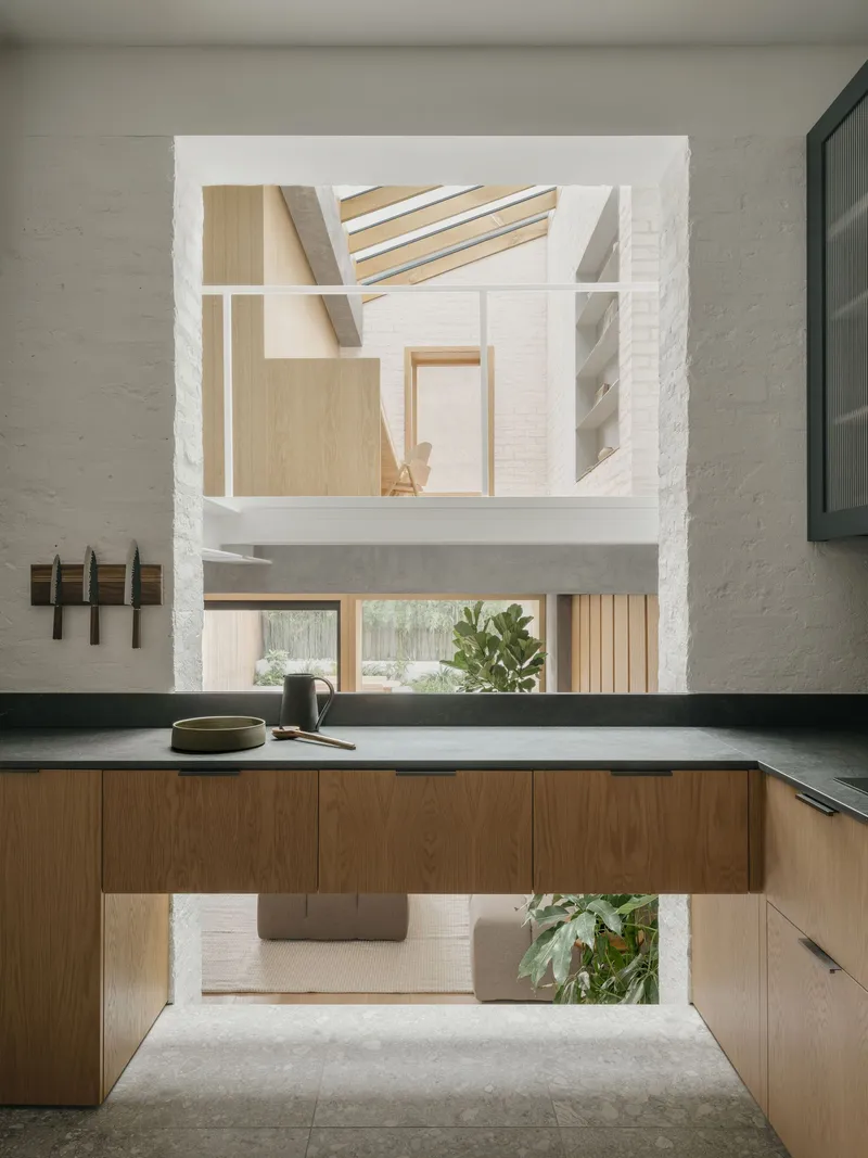 Kitchen island with dark countertop framing views through a vertical opening to the upper level