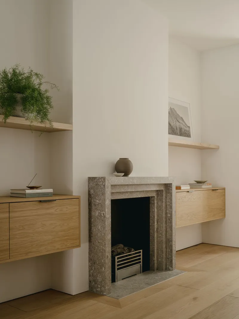 Grey stone fireplace surround flanked by suspended oak cabinetry and floating timber shelves