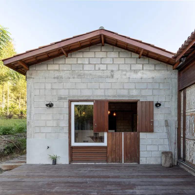 Exterior gable facade with concrete block walls, timber shutters and exposed rafters under overcast sky