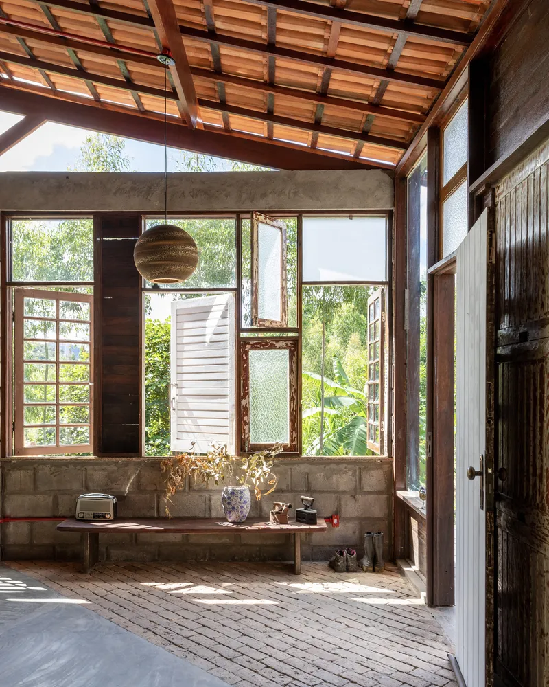 Corner of living area showing varied window types set into concrete block walls beneath timber rafters