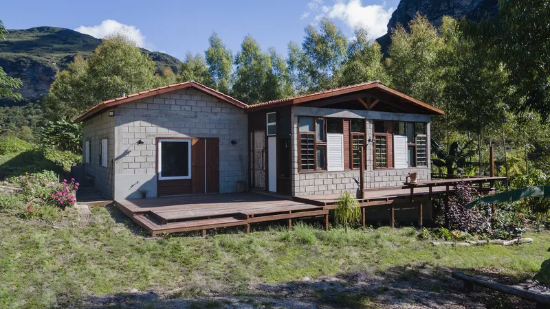 Concrete block house with timber gabled roofs and open deck facing forested mountain slopes