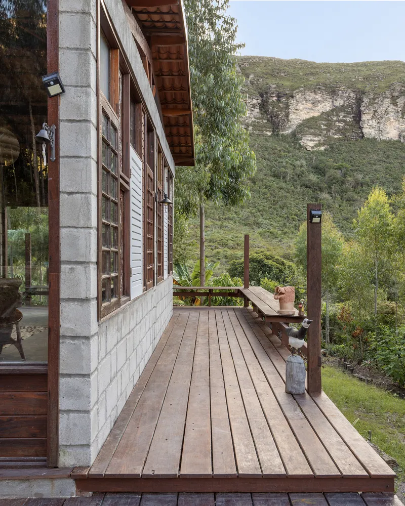 Timber deck with concrete block and wood siding facade overlooking green valley and mountain backdrop