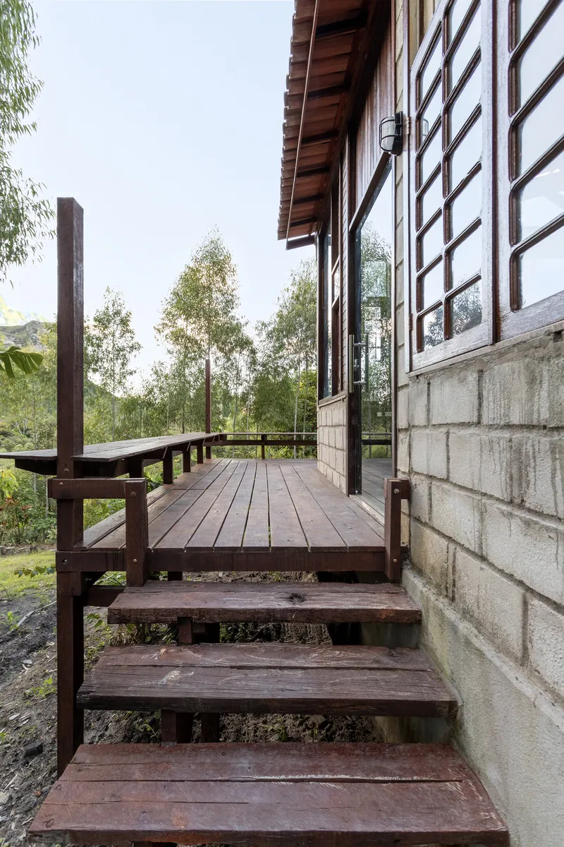 Timber stairs descending from elevated deck porch beside concrete block base and gridded window facade