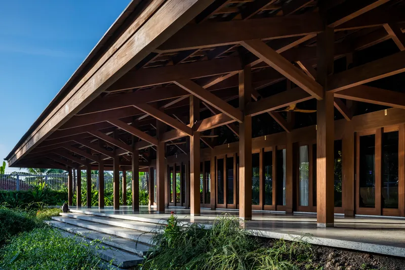 Exterior view of the deep eaves and timber columns along the planted edge under blue sky