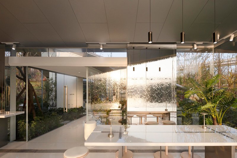 Interior view through glass walls toward water feature wall with planted courtyard visible beyond