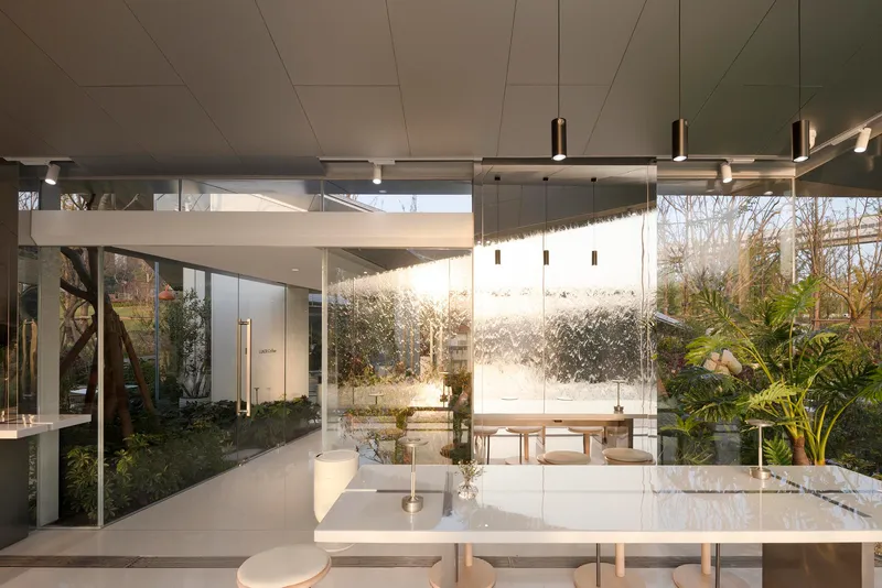 Interior view through glass walls toward water feature wall with planted courtyard visible beyond