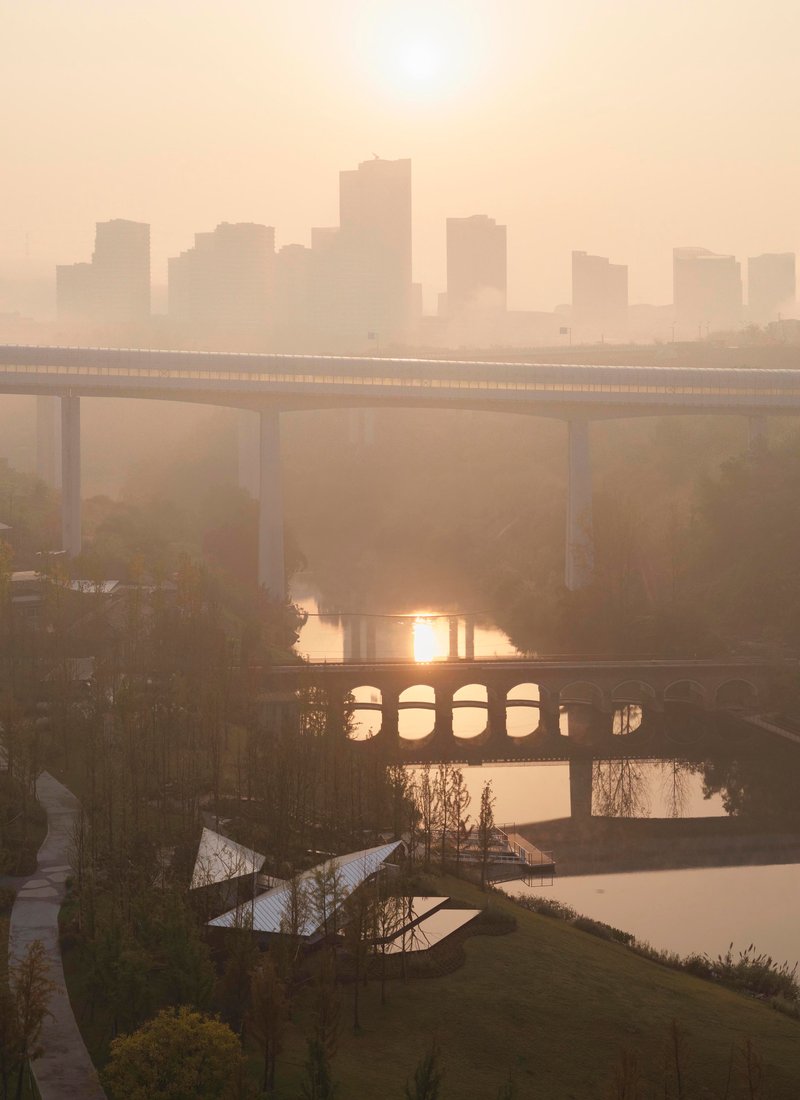 Layered bridges crossing a river with distant skyline silhouettes in heavy morning haze