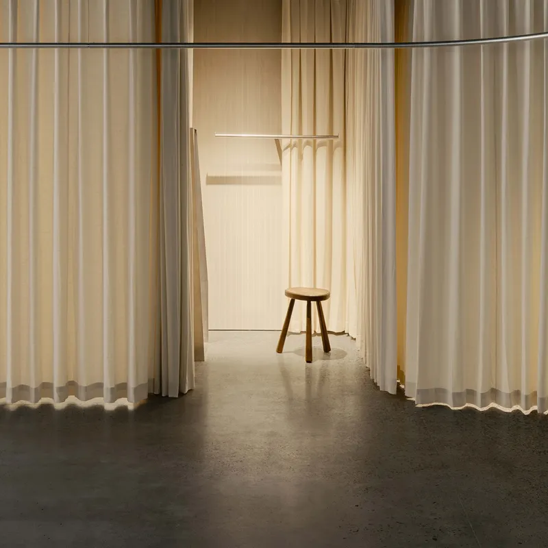Corridor framed by hanging curtains leading to a wooden stool and coat rack
