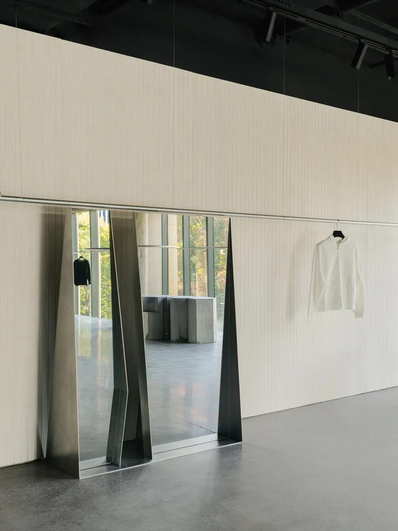 Trapezoidal doorway with folded metal jambs framing view into adjacent room with concrete columns