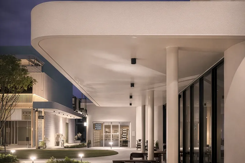 Covered exterior terrace with circular soffit and cylindrical columns at twilight