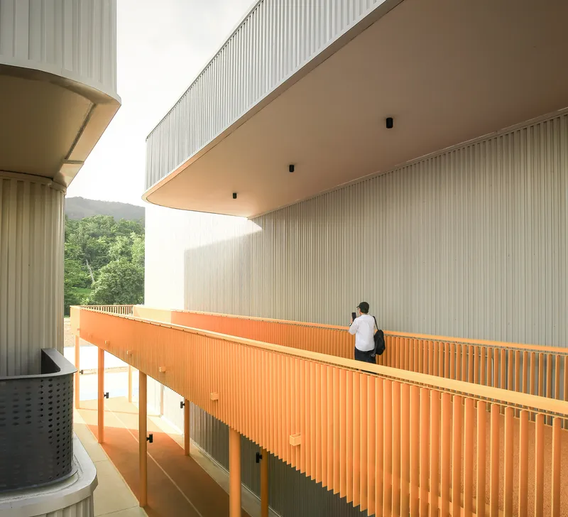 Elevated walkway with orange slatted railing and person leaning on the edge