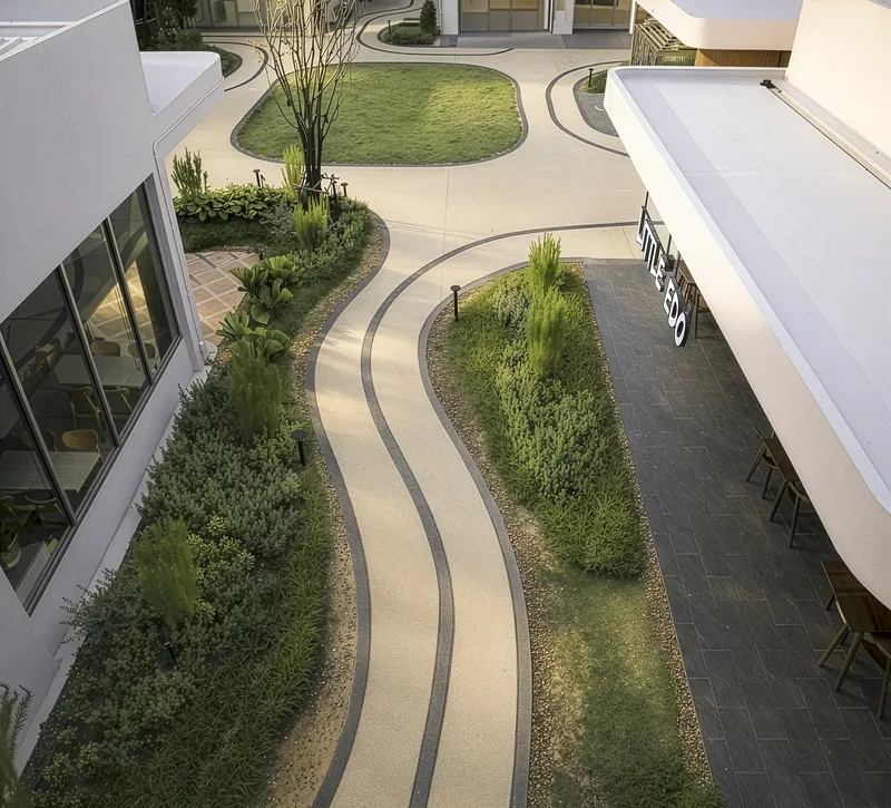 Aerial view of courtyard with curving planted beds and paved pathways between white roofed structures