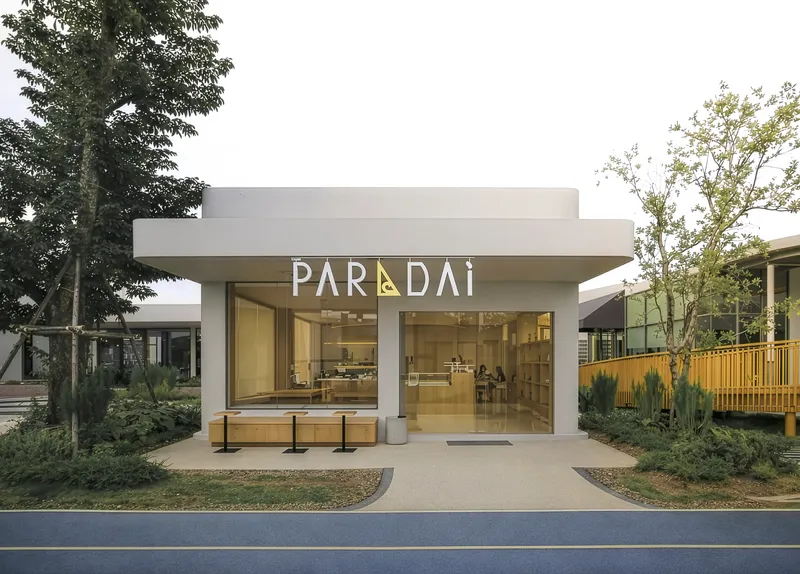 Entrance pavilion with recessed glazing framed by landscaped beds and young trees