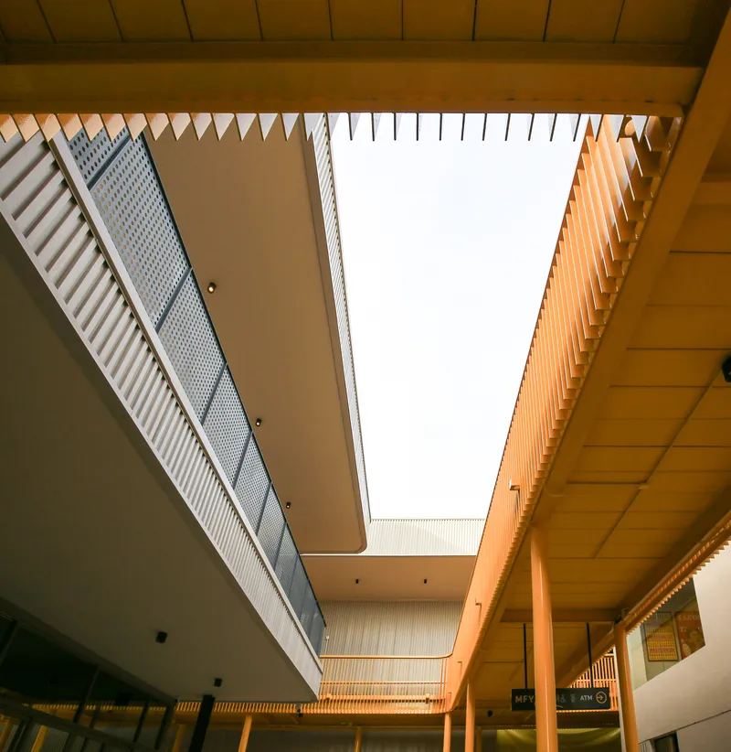 Interior courtyard looking up at rectangular skylight framed by timber ceiling and corrugated metal