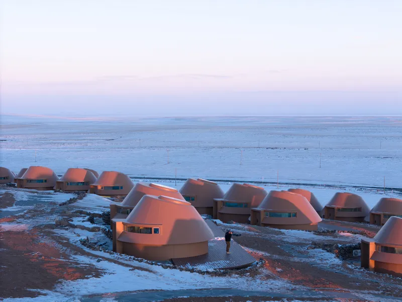 Cluster of domed units with ribbon windows in snow at dusk with a figure walking between them
