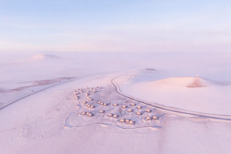 Drone view of the three-lobed settlement of dome structures in a misty snowfield