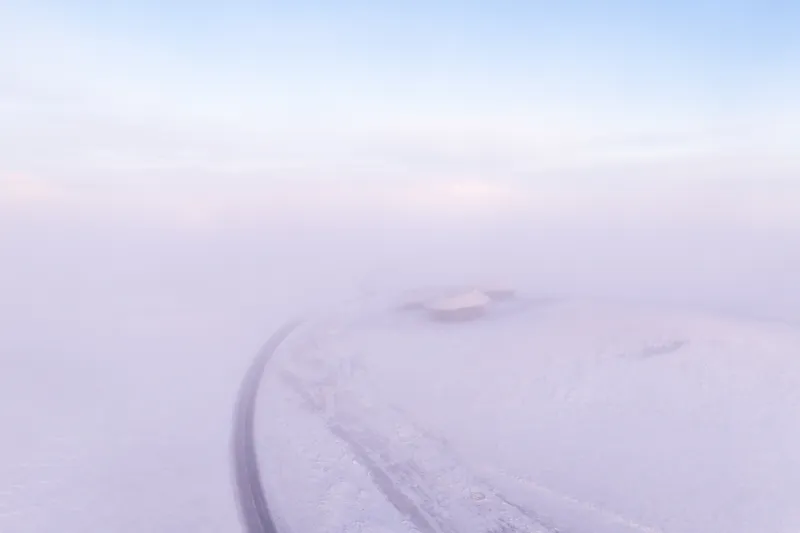 Misty distant view of the volcano cone with the road curving past it
