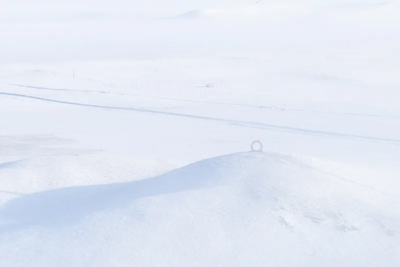 Distant horizon view of a tiny circular structure sitting on a low rise in the snow