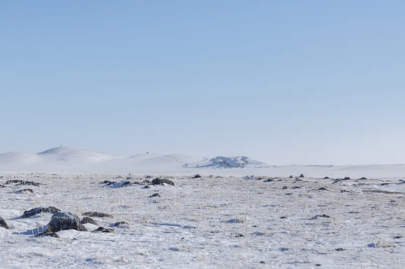 Wide view of the bare grassland horizon with low volcanic hills in the distance