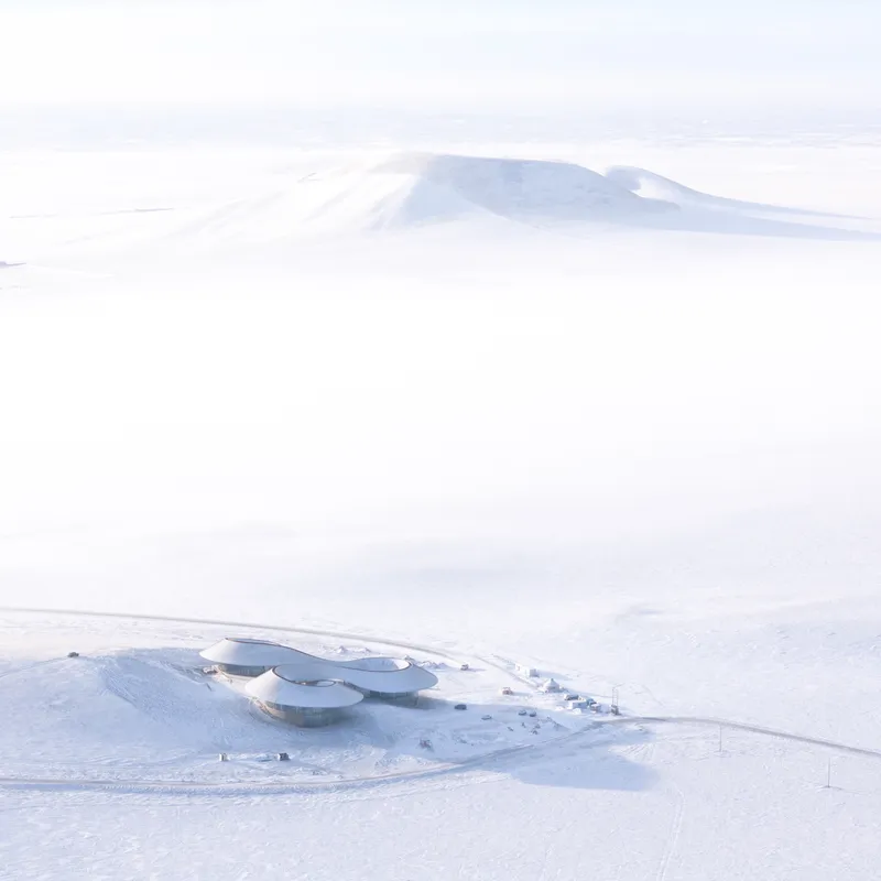 Distant aerial of the visitor center sitting in the snow with the extinct volcano cone behind