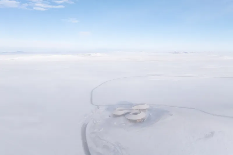 Drone view of the curving cloverleaf-shaped roof in a vast snowfield